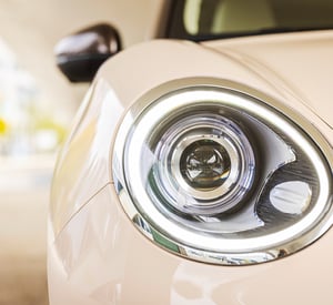 Detailaufnahme eines runden LED‑Scheinwerfers an einem hell lackierten GWM ORA 03, mit reflektierenden Chrom‑Elementen und weichem Umgebungslicht