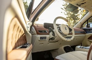 Innenraum eines GWM ORA 03 mit geöffnetem Fahrer­einstieg; helles Leder‑Interieur mit beigen und braunen Akzenten, modernem Armaturenbrett und Sonnenlicht, das durch die Tür hereinfällt.