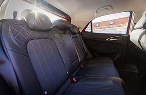 Hintere Sitzreihe eines GWM ORA 03 mit dunklem, gesteppem Leder und drei Kopfstützen; durch das Fenster fällt Sonnenlicht ins Innere.