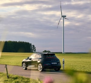 GWM ORA 03 SUV auf einer Straße vor grüner Landschaft und Windrädern